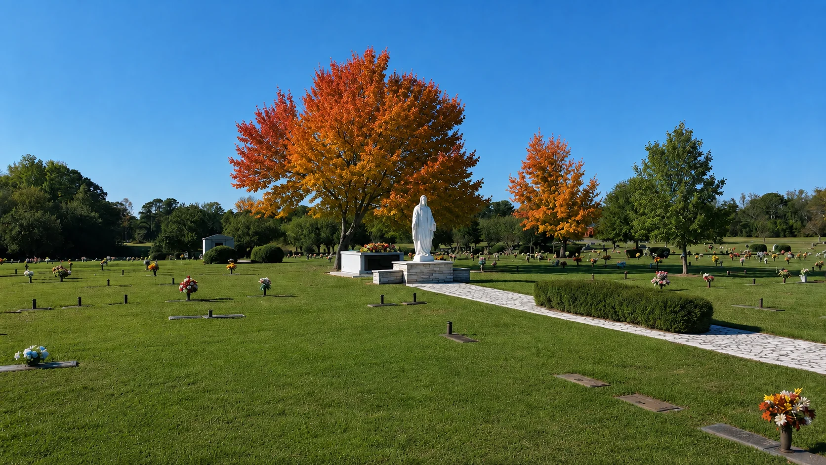 Autumn trees, flowers, and a white memorial statue in Pineview’s gardens